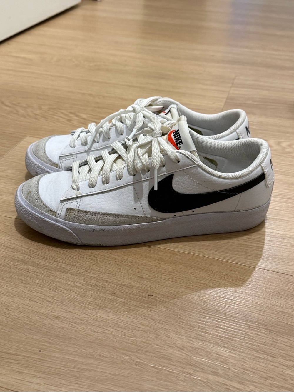 Nike White Low-Top Sneakers with Black Swoosh and Subtle Orange Tongue Detail